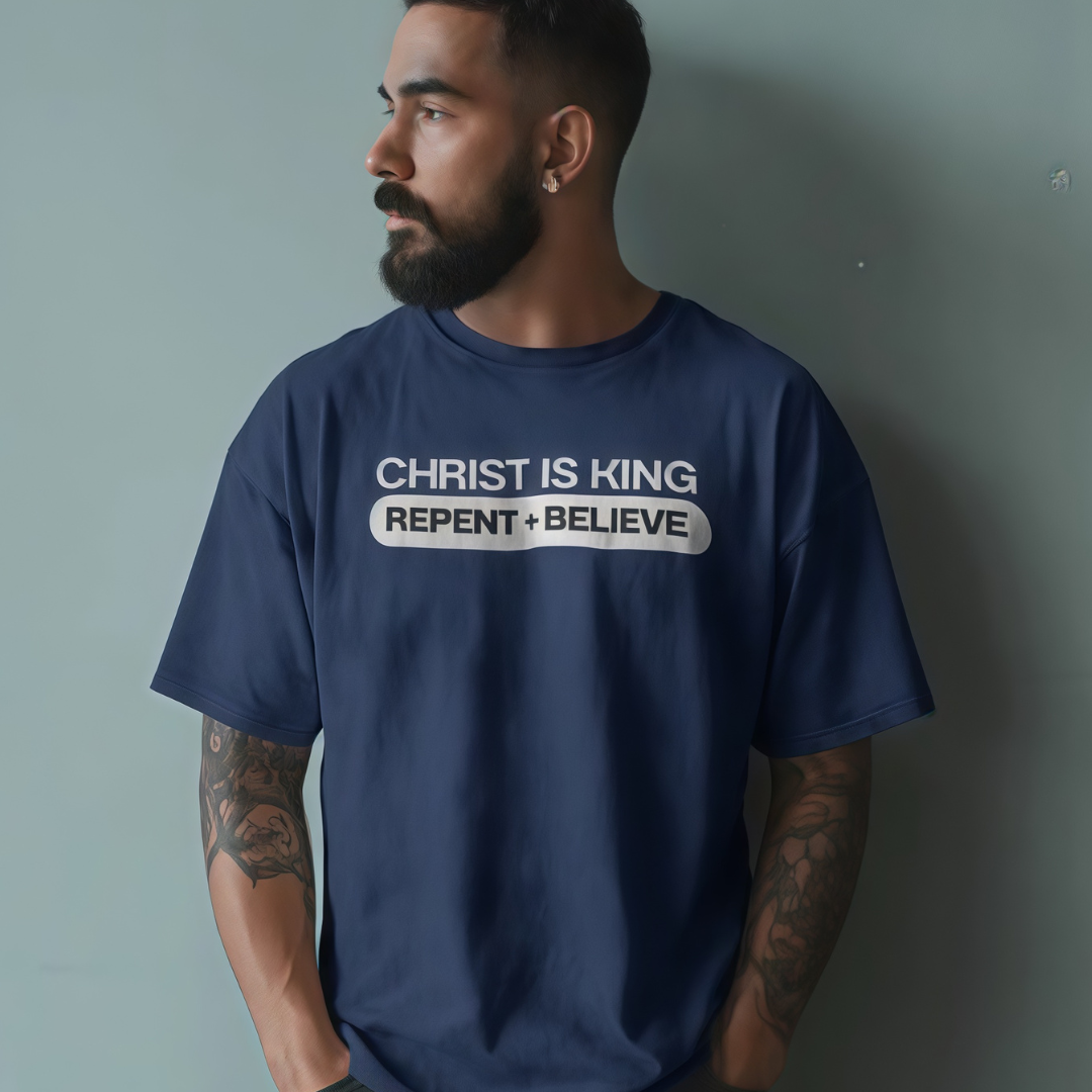 Man wearing a navy blue t-shirt with 'Christ is King' text against a gray background