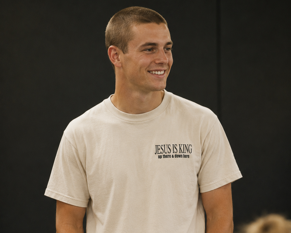 Man wearing a t-shirt with 'Jesus is King' text in a casual setting